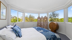 A bedroom with a large bed, a wooden wardrobe, and a round wooden cabinet. - POSITANO - MT MARTHA (MOUNT MARTHA)