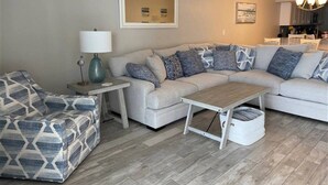 A living room with a sofa, a patterned armchair, a small table, and a lamp.