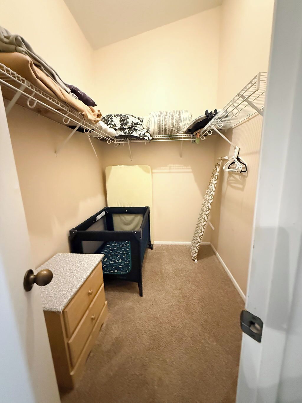 A small, narrow room with a closet containing hanging storage and a baby crib.