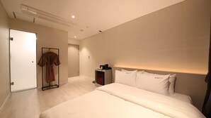 Une chambre d’hôtel moderne avec un grand lit, une table de chevet, un porte-peignoir et une porte.
