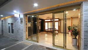 L’entrée d’un hôtel avec une porte en verre, un comptoir d’accueil et un espace salon à l’intérieur.