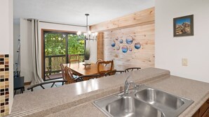 Una cucina con un lavello doppio, rivestimenti in legno e un'area pranzo con tavolo e sedie.