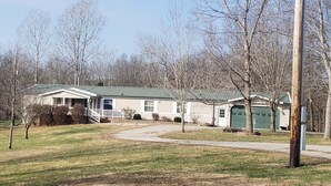 A single-story house with a green roof, a front porch, and a garage. - Lodge at the Longbranch next to the Longbranch Saloon (AVA)