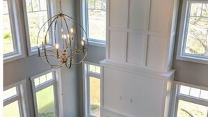 A room with a fireplace, large windows, and a hanging light fixture. - Luxury custom home long-stay family retreat in Shepherdstown (Shepherdstown)