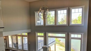 A spacious room with a high ceiling, large windows, and a chandelier. - Luxury custom home long-stay family retreat in Shepherdstown (Shepherdstown)
