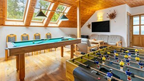 Un espacio interior acogedor con mesa de billar, mesa de futbolín y un sofá.