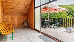 Un interior de madera con balcón, una mesa, sillas y un paraguas de Coca-Cola.