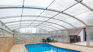 Una piscina techada con paredes de piedra y techo de cristal.