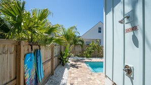 Ein Garten mit Pool, Holzzaun und einer Dusche.