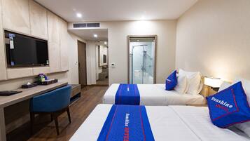A hotel room with two beds, a desk, a chair, a TV, and a shower area.