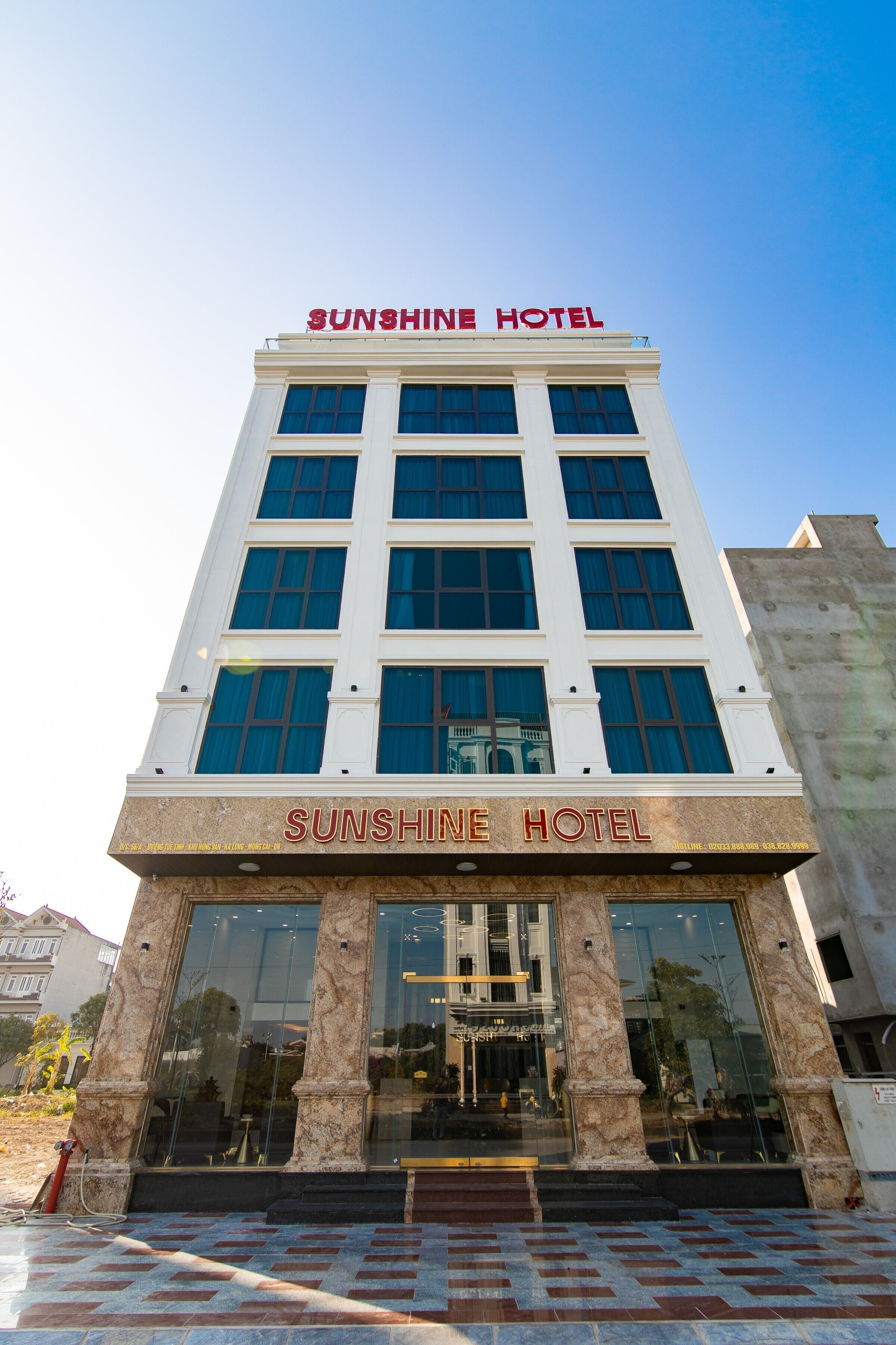 A multi-story building with the name "Sunshine Hotel" prominently displayed at the top and on the ground floor.