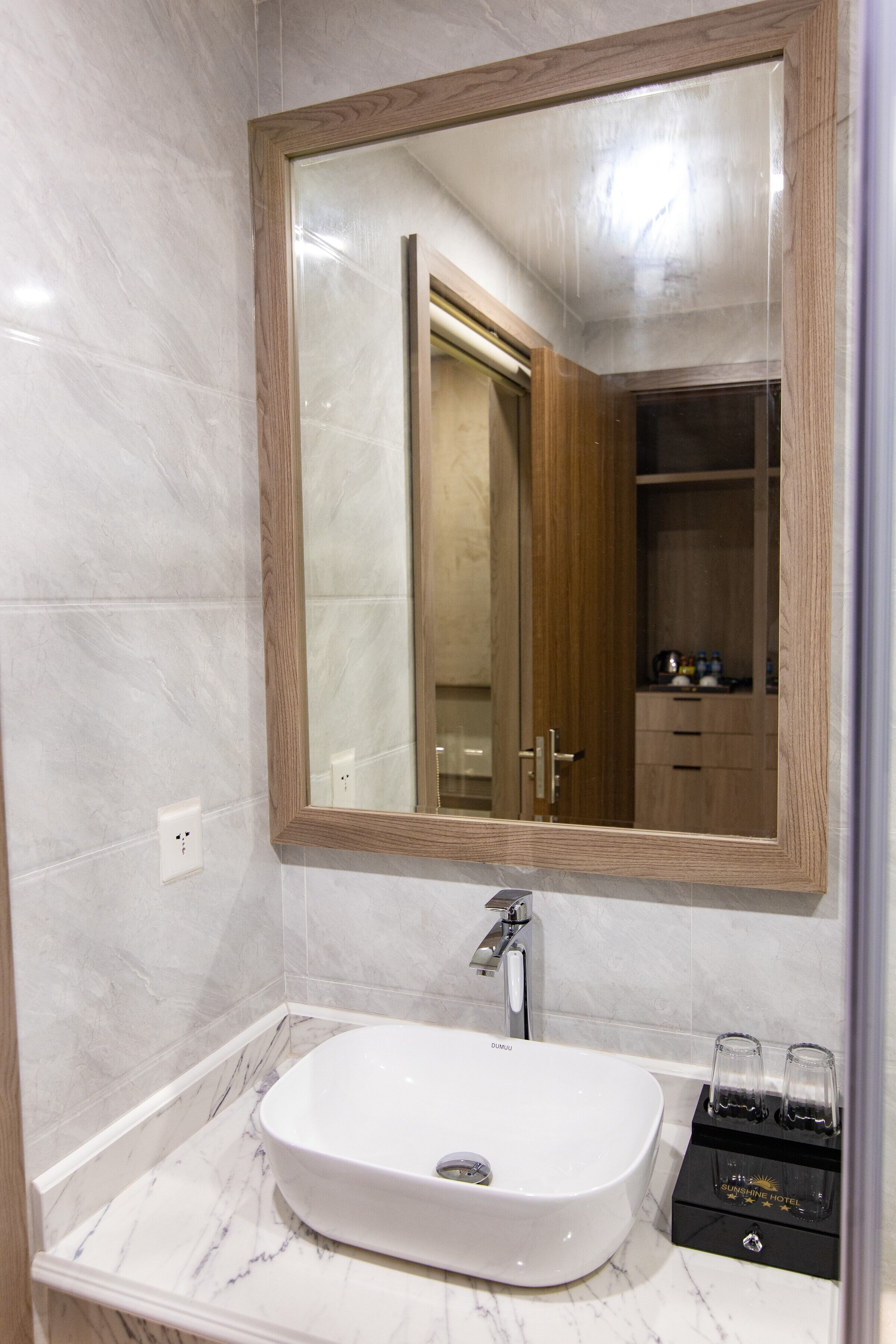 Un bany amb un lavabo blanc, un mirall i un armari de fusta.