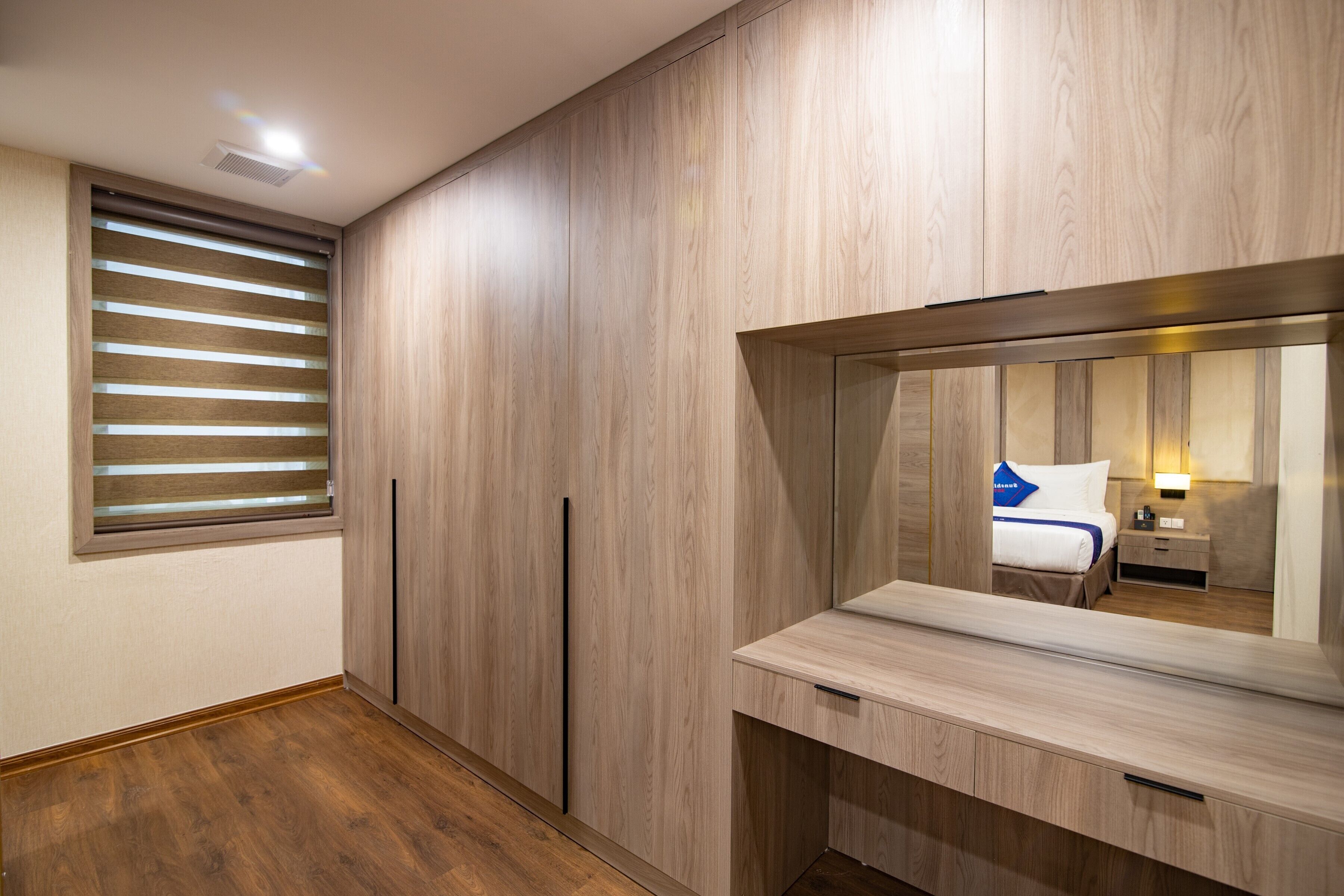 Un dormitorio con un espejo grande, un armario de madera y una mesita de noche.