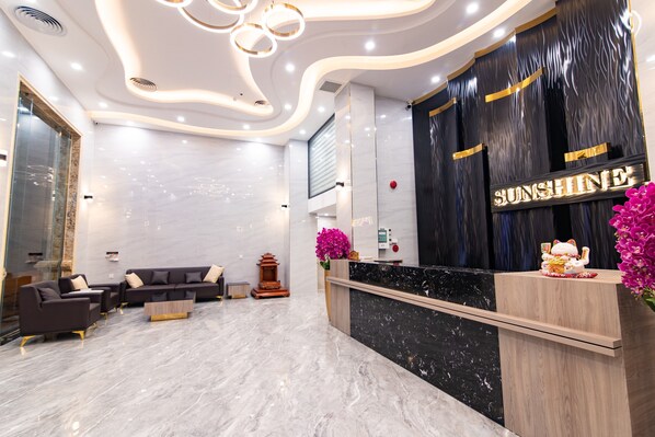 A modern reception area with a marble floor, a reception desk, and a seating area with sofas. - Sunshine Hotel (Mong Cai 2)