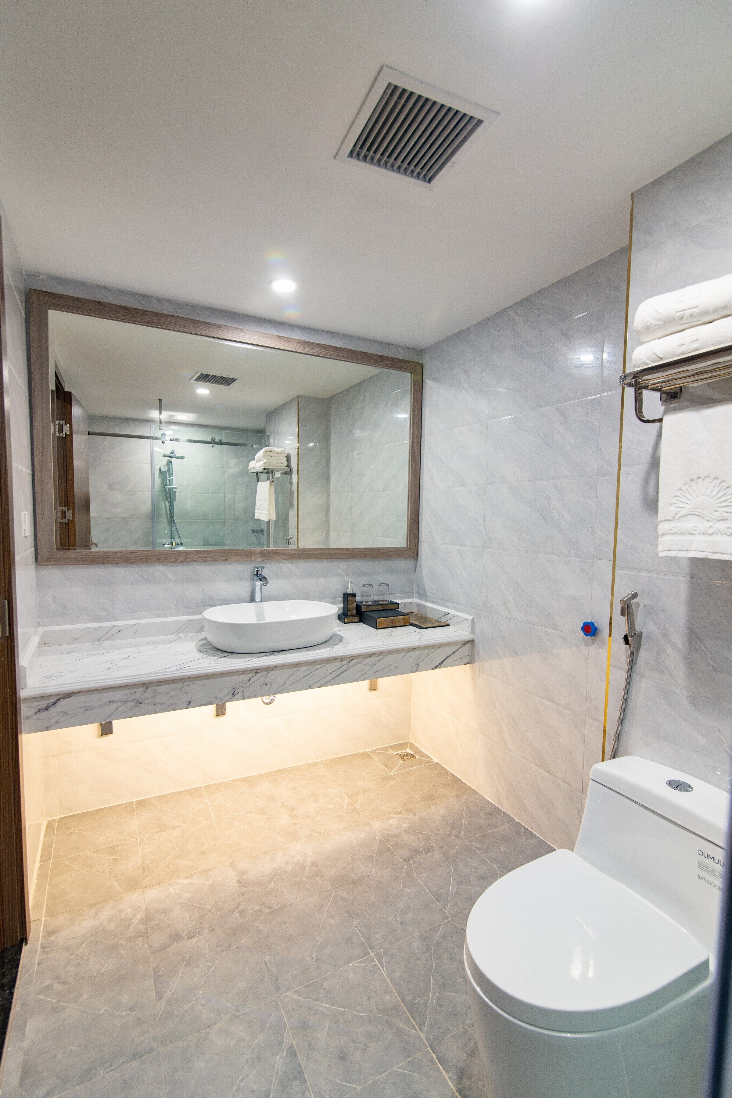 Un baño moderno con un espejo grande, un lavabo, un inodoro y una zona de ducha.