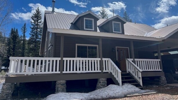 A two-story house with a covered porch and a chimney. - On the river close to all adventure and short drive to Durango (D&S Train/Mesa Verde/Million Dollar HWY) (Bayfield)
