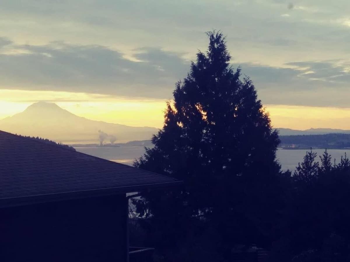 A house with a view of a mountain and a lake at sunset.