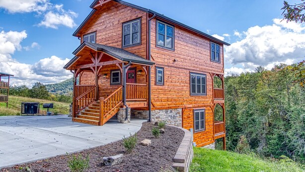 A two-story log cabin with a porch, a staircase, and a stone foundation. - Modern Smoky Mtn Cabin, Hot Tub, Game Room, Pool Table, Near Dollywood (Sevierville)