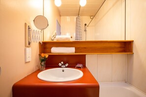 Een bad/douchecombinatie, een haardroger, handdoeken