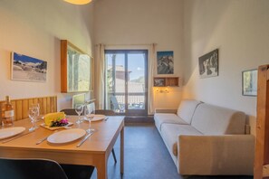 Een eetgedeelte met een gedekte tafel voor twee, een bank en een balkon met uitzicht.