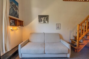 Ein Zimmer mit einer Couch, einer Treppe und Wandbildern.