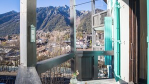 A balcony with a view of mountains, a wooden railing, and a table with a vase and bread. - Cham Sud Balme401 Family 2BR Walk to Lifts & Centre, Chamonix, France (Chamonix)