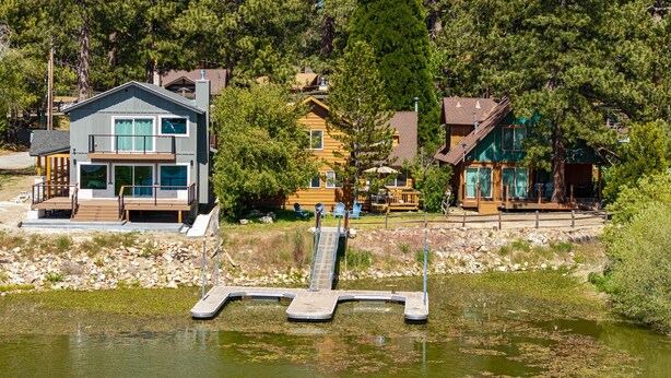Une propriété au bord du lac, dotée d’un quai, de maisons modernes et bordée d’une forêt.