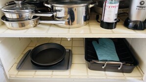 Une cuisine équipée d’ustensiles de cuisine en acier inoxydable, d’une machine à café et d’une bouilloire posées sur le plan de travail.