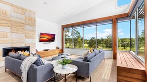 Uma sala de estar moderna com lareira, janelas amplas e vista para o exterior.