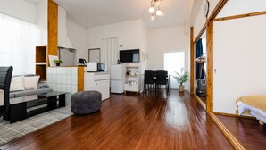 Een moderne woonkamer met een bank, een voetenbankje en een eethoek met stoelen en een tafel.