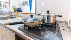 Een keuken met een fornuis, twee pannen en een gootsteen.