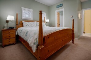 A four-poster bed with a wooden headboard and footboard, a nightstand with a lamp, and a dresser with drawers. - Fantastic Coastal Getaway, Open Floor Plan, Steps Away From Beach, Fireplace, BBQ, Ocean Views (Depoe Bay)