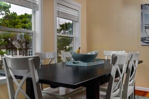 A dining area with a black table, white chairs, and a blue bowl with bananas. - Fantastic Coastal Getaway, Open Floor Plan, Steps Away From Beach, Fireplace, BBQ, Ocean Views (Depoe Bay)