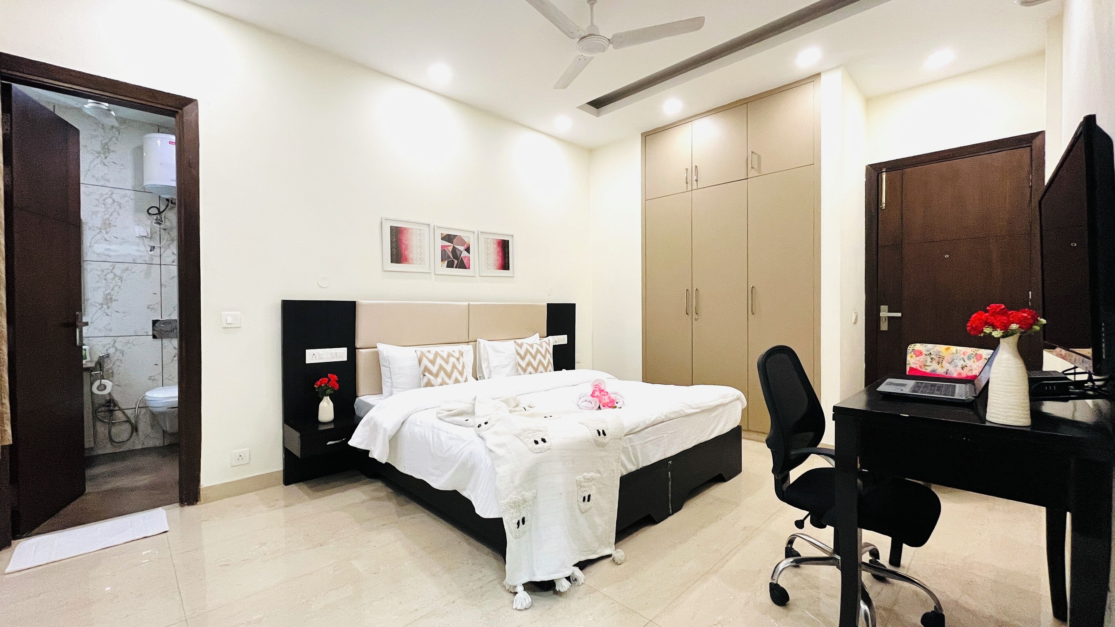 A bedroom with a bed, a desk, a chair, a wardrobe, and a shower area.