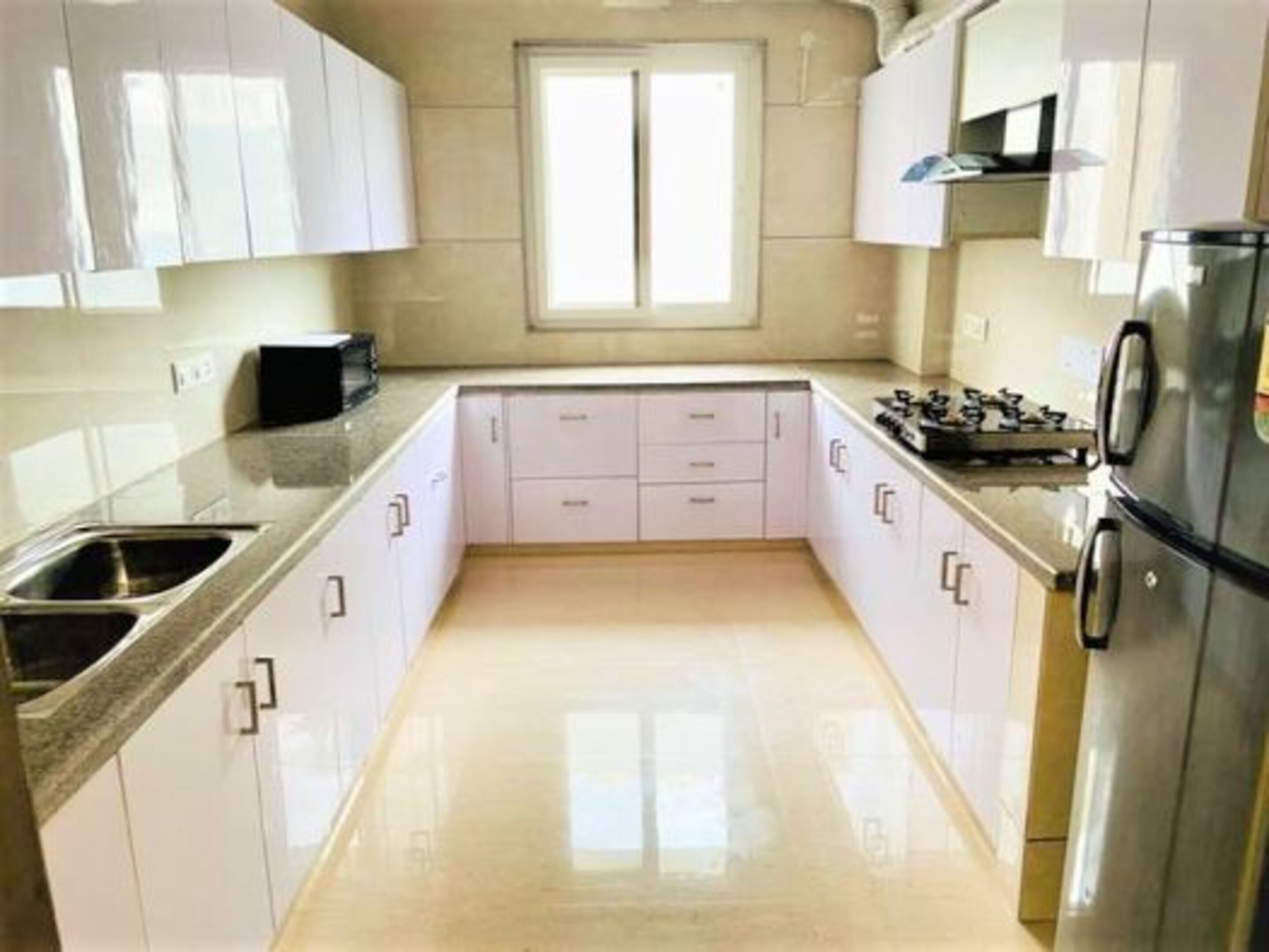Una cocina moderna con armarios blancos, un lavamanos de acero inoxidable y un horno empotrado.