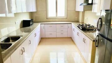 Una cocina moderna con armarios blancos, un lavamanos de acero inoxidable y un horno empotrado.