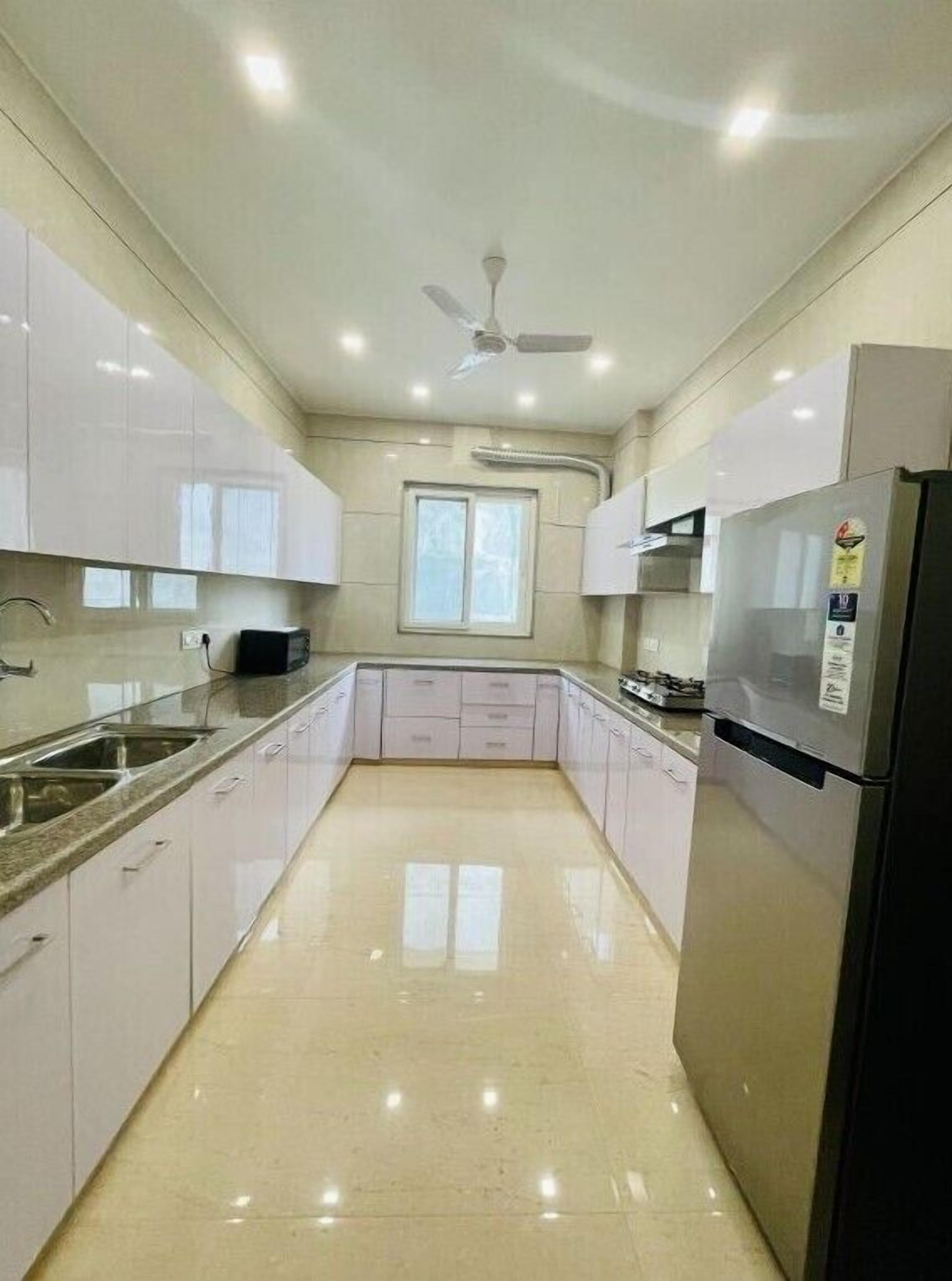 A modern kitchen with white cabinets, a stainless steel refrigerator, and a ceiling fan.