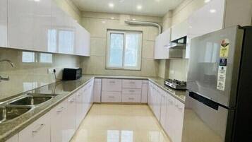 A modern kitchen with white cabinets, a stainless steel refrigerator, and a ceiling fan.