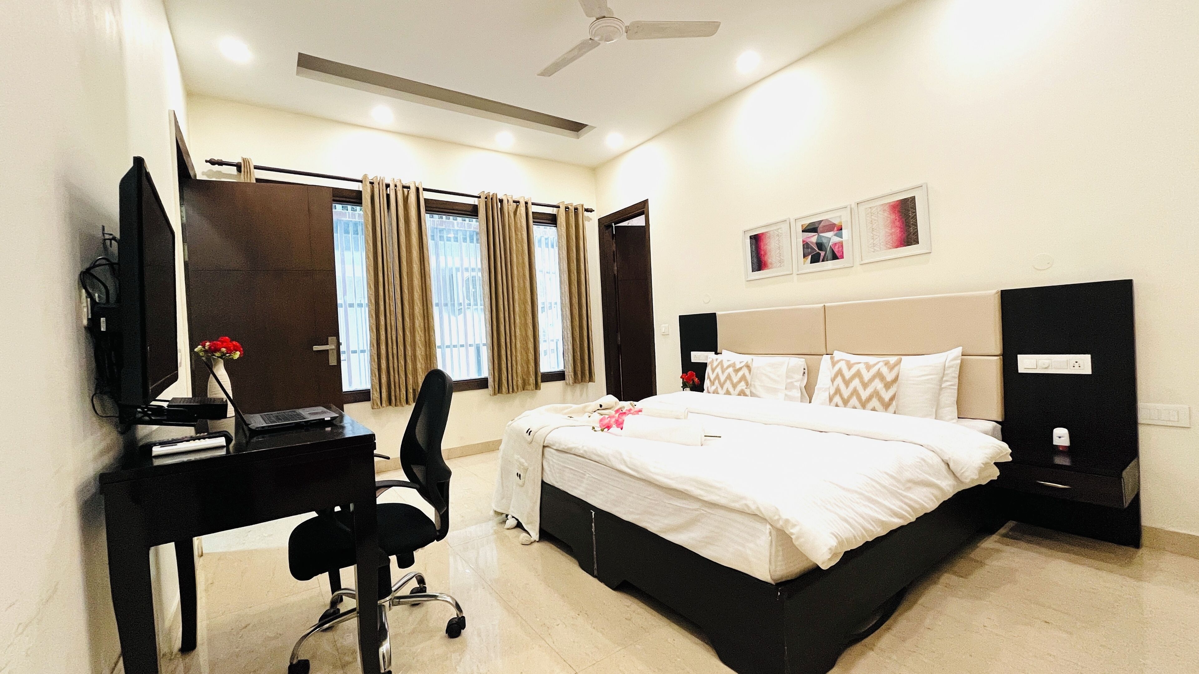 A hotel room with a bed, desk, chair, and a ceiling fan.