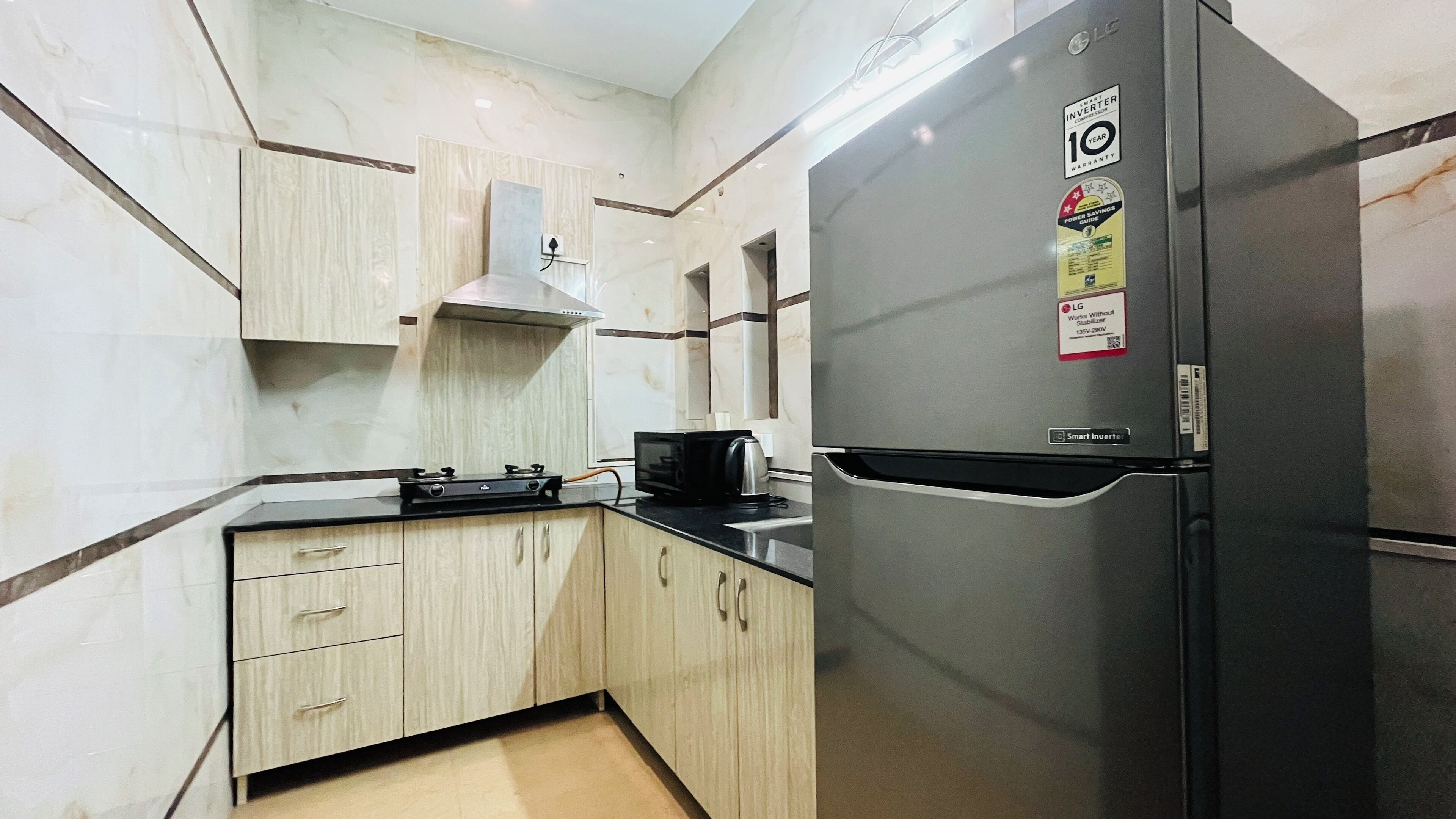 A kitchen with a stainless steel refrigerator, a microwave, and a gas stove.