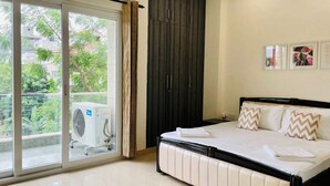 Et soveværelse med seng, skydedør til en balkon og en aircondition.
