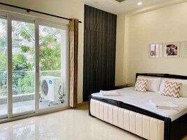 Un dormitorio con cama, puerta corredera a un balcón y aire acondicionado.
