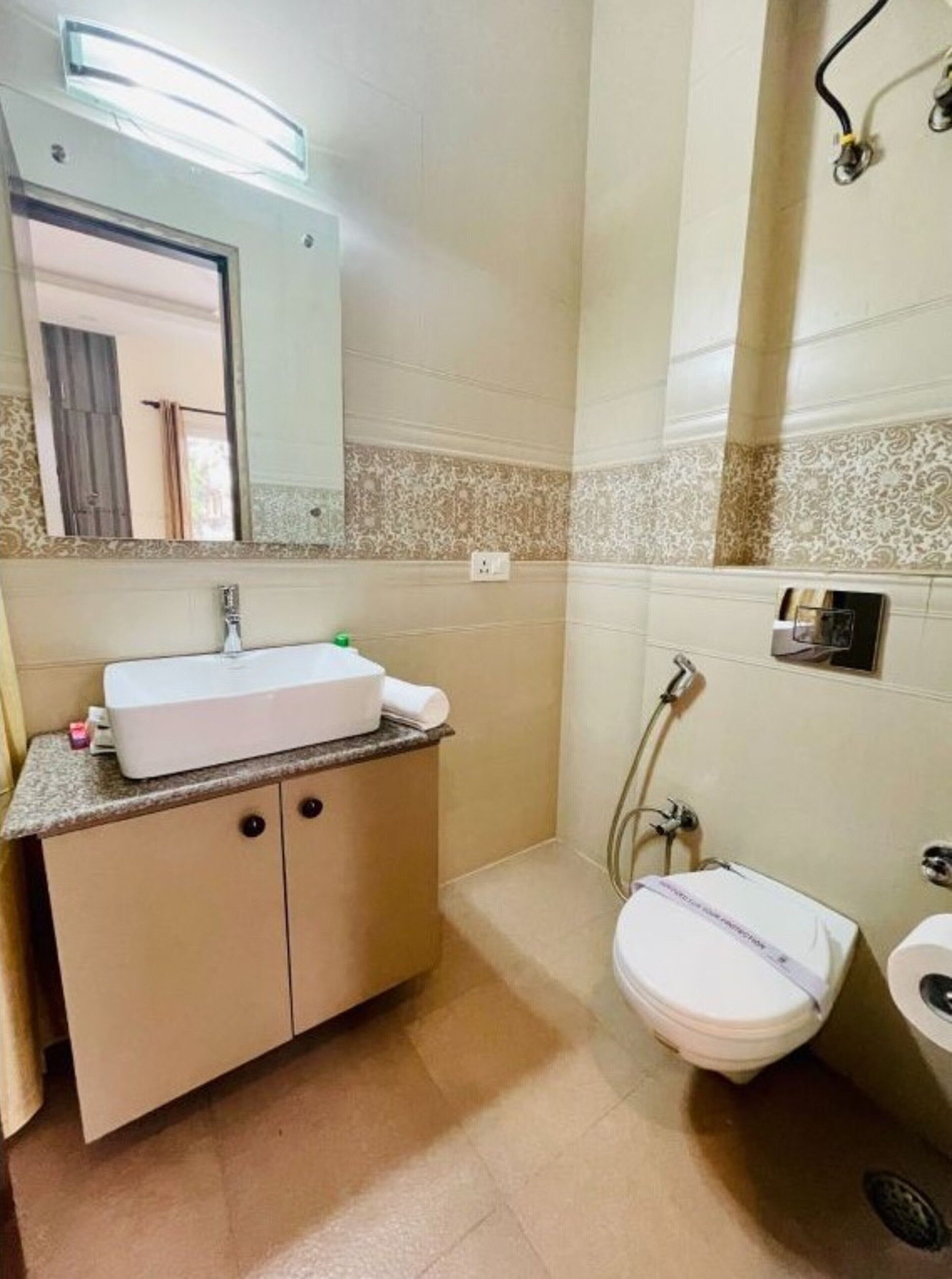 Casa de banho com lavatório branco, espelho e sanita.