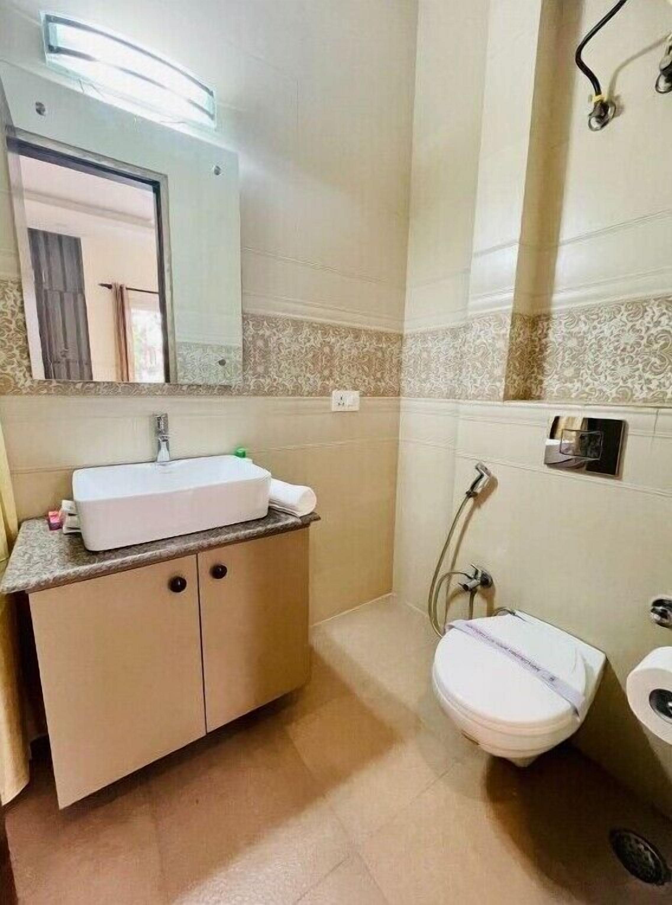 A bathroom with a sink, mirror, toilet, and shower.