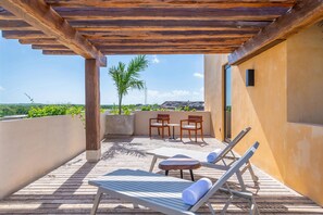 A wooden deck with lounge chairs and a table, overlooking a scenic landscape. - Aloft Tulum (Tulum)