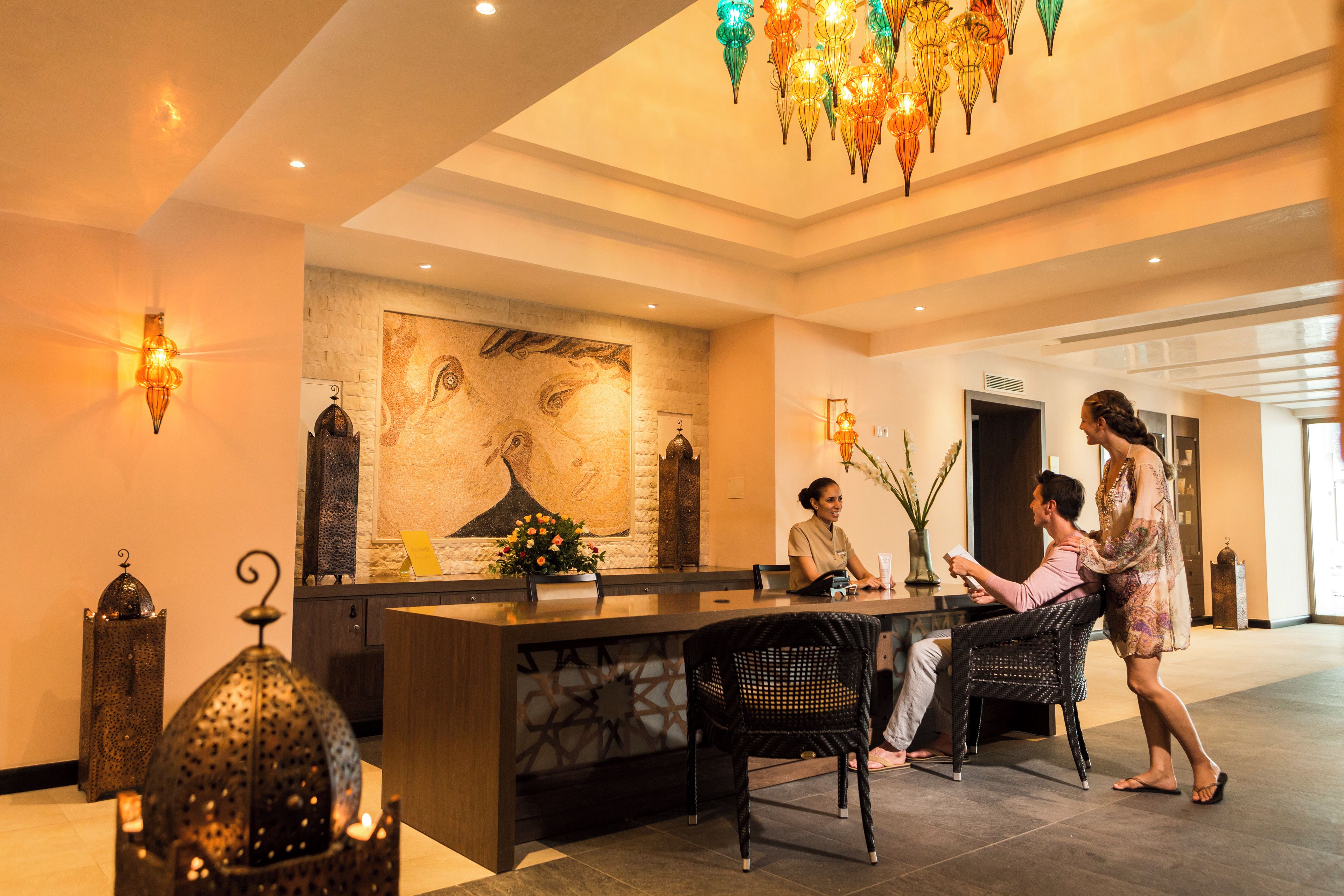 A reception area with a stone counter, a large abstract painting, and a chandelier.