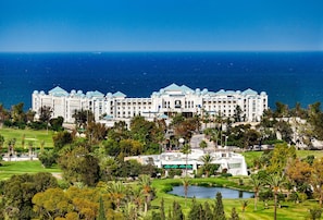 Un hotel grande y blanco con múltiples cúpulas, ubicado en una zona costera con vista al mar.