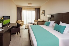 Une chambre d’hôtel avec un grand lit, un bureau avec une télévision, un canapé et une table basse.