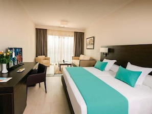 Ein Hotelzimmer mit Bett, Schreibtisch, Stühlen und einem Gemälde an der Wand.