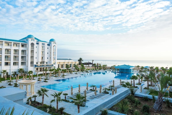 A resort with a large pool, palm trees, and a view of the ocean.